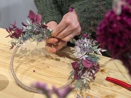 Adventskranz Adventskranz mit grünen Blättern, roten Blüten und goldenen Kerzenhaltern.