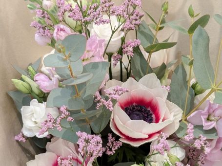 Brautstrauß Strauß aus weißen und lila Blumen, darunter Rosen und Lilien, auf einem Holzuntergrund.
