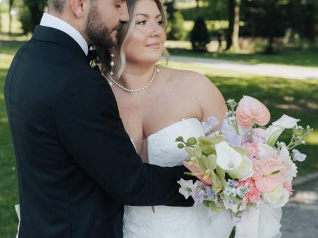Strauß aus weißen und lila Blumen, darunter Rosen und Lilien, auf einem Holzuntergrund.