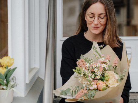 Bunter Brautstrauß mit lila, rosa und weißen Blüten auf einem holzigen Untergrund.