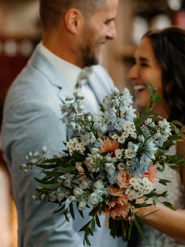 Brautstrauß Braut hält einen bunten Blumenstrauß mit blauem, rosa und weißem Blumenschmuck.