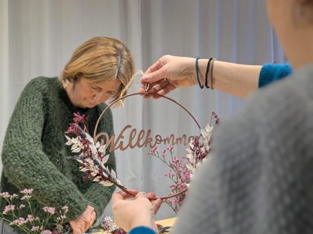 Adventskranz binden Grüne Pflanzen, rote Beeren und Bindematerial liegen auf einem Tisch.