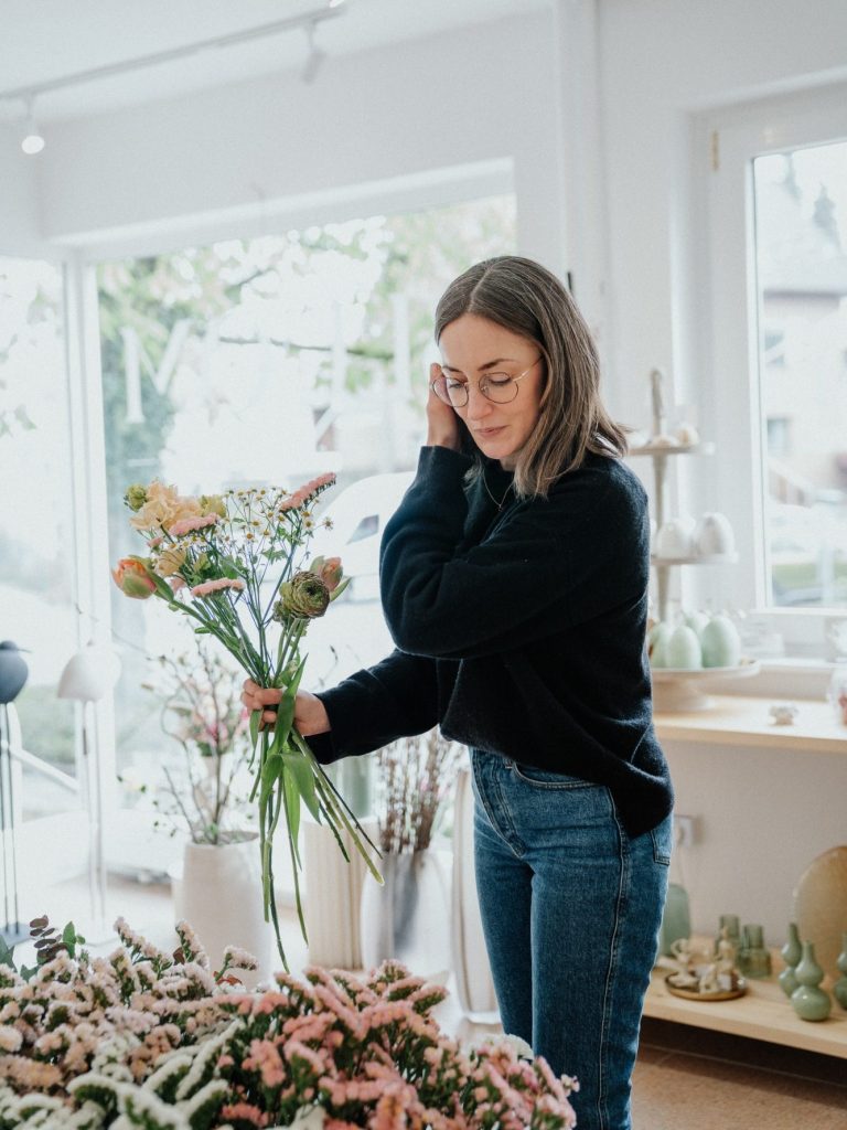 Braut hält einen bunten Blumenstrauß mit blauem, rosa und weißem Blumenschmuck.